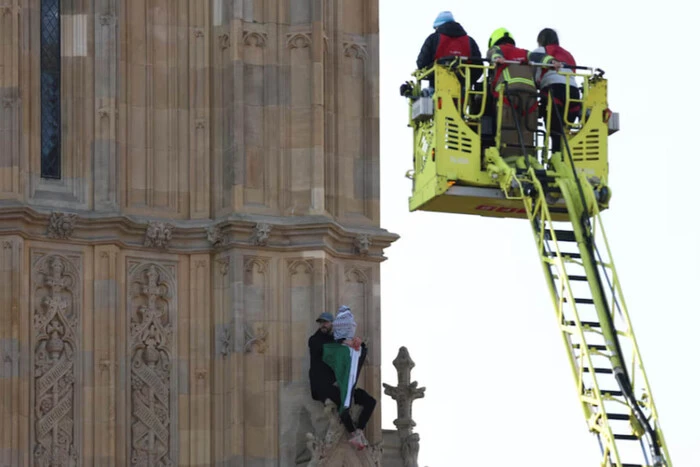 A barefoot man with a Palestinian flag on Big Ben