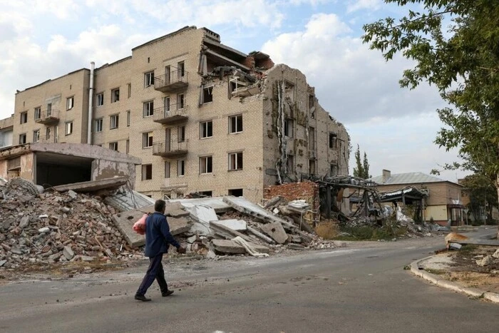 Evacuation vehicle with cargo against the background of a burnt hospital